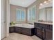 Bright bathroom featuring a corner soaking tub with tile surround and dark wood cabinets at 27625 E Moraine Dr, Aurora, CO 80016