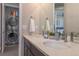 A modern bathroom featuring a double sink vanity, a large mirror, and a convenient stacked washer/dryer at 10177 E 62Nd Ave, Denver, CO 80238