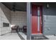 Welcoming front porch with seating area, modern red front door, and stylish exterior lighting at 10177 E 62Nd Ave, Denver, CO 80238