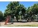 Community playground with a slide and swing set surrounded by trees at 9942 Lane St, Thornton, CO 80260