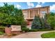 Exterior view of apartment building with lush landscaping, sign with address, and a clear sky in the background at 5677 S Park Pl # D310, Greenwood Village, CO 80111