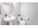 Charming half-bathroom features a stylish pedestal sink, a round mirror, and clean white walls at 4760 Kittredge St, Denver, CO 80239
