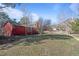 Backyard view showcasing a red home exterior surrounded by lush greenery and trees at 96 Greeley Blvd, Palmer Lake, CO 80133