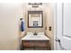 Well-lit powder room with a decorative wood mirror, white quartz counters, and a stylish dark wood vanity at 11363 Jersey St, Thornton, CO 80233