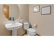 Clean bathroom features a pedestal sink, modern toilet, decorative art, and neutral paint at 1898 Wilson Cir, Erie, CO 80516