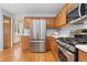 Modern kitchen featuring stainless steel appliances, wood cabinets, and tile countertops with a view of the backyard at 1898 Wilson Cir, Erie, CO 80516