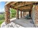 Covered patio with stone pillars, a concrete floor, and wood ceiling offers a relaxing outdoor space at 1385 Candleglow St, Castle Rock, CO 80109