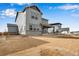 A view of a two-story gray home's back yard with a covered patio, large unfinished area, and neighboring houses at 24661 E 33Rd Dr, Aurora, CO 80019