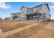 Two story gray home featuring a covered porch and stone accents, with a spacious unfinished yard under a blue sky at 24661 E 33Rd Dr, Aurora, CO 80019