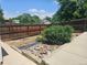 Wooden fenced backyard has mature bush, rock bed and concrete sidewalk at 2707 S Richfield St, Aurora, CO 80013