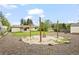 Wide backyard features a fire pit and gravel area, all under a bright, cloud-filled sky at 6147 Dunraven St, Golden, CO 80403