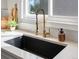 Close-up of a kitchen sink with brass fixtures, white counters, and subway tile backsplash at 8425 Green Island Cir, Lone Tree, CO 80124