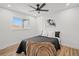 Cozy bedroom featuring light wood floors, a ceiling fan, and a bright window at 2341 Poze Blvd, Thornton, CO 80229