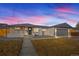 Charming home at dusk featuring a well-maintained yard, painted brick, and a gray two-car garage at 2341 Poze Blvd, Thornton, CO 80229