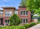 Exterior view of two-story townhome featuring red brick and stucco, with lush greenery at 8983 E Nichols Pl, Centennial, CO 80112