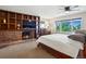 Comfortable bedroom with a brick fireplace feature and a large window overlooking the lush green backyard at 8387 N Sunburst Trl, Parker, CO 80134