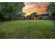 Well-maintained backyard showcases a brick home exterior, large lawn, and serene sunset ambiance at 2644 S Krameria St, Denver, CO 80222