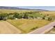 Scenic aerial view showcasing a vast property with green fields, outbuildings, and mature trees at 6145 S Perry Park Rd, Sedalia, CO 80135