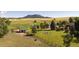 Beautiful rural property featuring green pastures, fencing, outbuildings, and mature trees with mountain backdrop at 6145 S Perry Park Rd, Sedalia, CO 80135