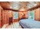 Bedroom with knotty pine walls, hardwood floors and two windows overlooking the yard at 6145 S Perry Park Rd, Sedalia, CO 80135