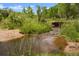 Picturesque view of a gentle creek flowing through lush greenery and sandy banks at 6145 S Perry Park Rd, Sedalia, CO 80135