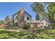 Charming home with a stone chimney and lush landscaping, set against a clear blue sky at 6145 S Perry Park Rd, Sedalia, CO 80135