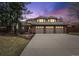 Attractive two-story home featuring a brick facade, three-car garage, and a beautifully landscaped front yard at twilight at 5797 S Laredo Ct, Centennial, CO 80015