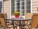 Cozy outdoor seating area with a glass-top table, four chairs, and a colorful flower centerpiece at 9810 Mulberry Way, Highlands Ranch, CO 80129