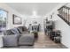 Bright living room featuring hardwood floors, staircase, a modern sofa, and a view into dining area at 12606 Fairfax St, Thornton, CO 80241