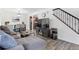 Open-concept living room showcasing hardwood floors, staircase, a modern sofa, and an adjacent dining area at 12606 Fairfax St, Thornton, CO 80241