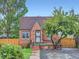 Quaint brick home with a landscaped front yard, secure iron gate, and mature shade tree at 1351 Brentwood St, Lakewood, CO 80214