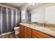 Bathroom with double sinks, granite counters and wood cabinets, plus shower and bath combination with curtain at 4935 S Zephyr St, Littleton, CO 80123