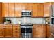 Kitchen featuring stainless steel appliances, light granite countertops, and wooden cabinets at 4935 S Zephyr St, Littleton, CO 80123