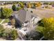 Aerial view of the home and well-manicured lawn surrounded by autumn foliage at 10044 E 146Th Pl, Brighton, CO 80602