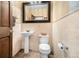 Small powder room features pedestal sink, toilet, and decorative mirror with stylish wallpaper and tile at 10044 E 146Th Pl, Brighton, CO 80602