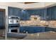 A well-equipped kitchen featuring blue cabinets, stainless steel appliances, and tile backsplash at 10044 E 146Th Pl, Brighton, CO 80602