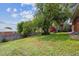 Large backyard featuring a grassy lawn, mature trees, a wood fence, and a red shed on a sunny day at 10452 Washington Way, Northglenn, CO 80233