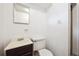 Small bathroom featuring a white toilet and a sink vanity with brown cabinets, all against a clean white wall at 10452 Washington Way, Northglenn, CO 80233