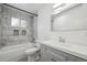 Bright bathroom featuring a marble tile shower-tub combo, a gray vanity, and a modern rectangular mirror at 10452 Washington Way, Northglenn, CO 80233
