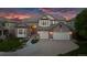 Elegant brick home with a three-car garage, landscaped front yard, and warm exterior lighting at 6095 S Oswego St, Greenwood Village, CO 80111