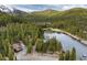 Aerial view of a lakefront property surrounded by lush green trees with lake and mountain views at 159 Lake Rd, Idaho Springs, CO 80452