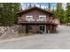 Charming two-story cabin with a large deck surrounded by lush greenery and a red barn at 159 Lake Rd, Idaho Springs, CO 80452