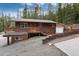 Exterior two-story cabin with a deck and garage nestled in a wooded area with a gravel driveway at 159 Lake Rd, Idaho Springs, CO 80452