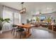 Elegant dining area with a wooden table, modern chandelier, and a view into the adjacent living room at 27893 E 6Th Pl, Aurora, CO 80018