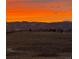 Serene backyard view with an orange sunset and distant snow-capped mountains at 10258 Pennington Ln, Highlands Ranch, CO 80126