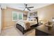 Comfortable bedroom with a dark wood bed frame, neutral bedding, ceiling fan and a bright window at 10258 Pennington Ln, Highlands Ranch, CO 80126