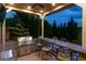 Covered outdoor kitchen with a built-in grill, bar seating, and granite countertops at 10258 Pennington Ln, Highlands Ranch, CO 80126
