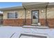 Inviting front entrance of brick home with charming details and snow-covered steps at 3420 Tennyson St # 105, Denver, CO 80212