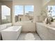 Bright bathroom featuring a soaking tub, double vanity, and large window at 6196 Oxford Peak Ln, Castle Rock, CO 80108