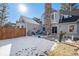 Backyard featuring a stone patio, a stone fireplace, and snow-covered grass at 10000 E Yale Ave # 7, Denver, CO 80231
